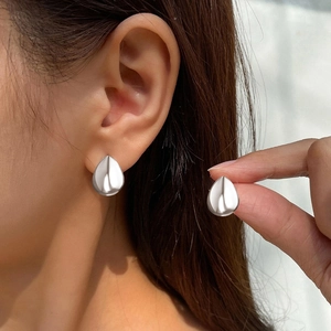 Detailed view of polished silver water drop earrings worn to show size and sleek metallic finish