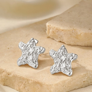 Gros plan détaillé de boucles d'oreilles étoile en argent avec texture froissée