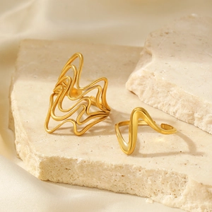 Detail of two layered gold wavy rings on stone base with soft fabric backdrop