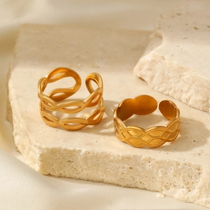 Detailed view of dual-layer wavy and geometric gold adjustable rings on stone background