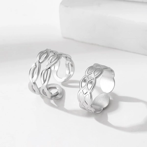 Silver woven and geometric hollow open rings set on a white stone pedestal