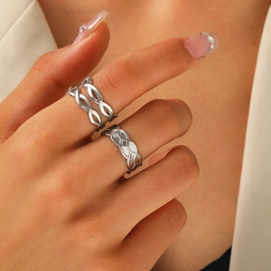 Close-up of interlocking infinity and geometric mesh silver-tone rings on finger