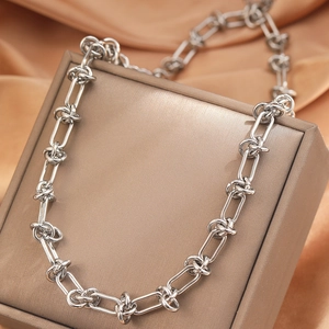 Polished silver stainless steel knotted chain necklace on luxury silk jewelry display