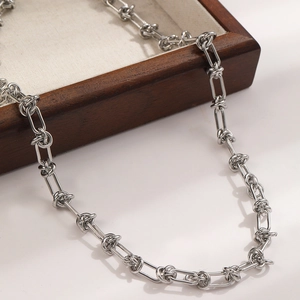 Detail of silver knot chain necklace featuring interconnected rectangular and twisted rings
