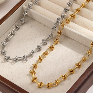 Minimalist stainless steel knotted link necklaces in gold and silver on a wooden jewelry box