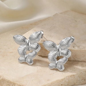 Close-up of silver butterfly titanium steel earrings with layered wing texture