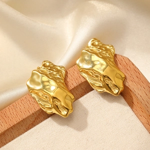 Polished gold irregular textured metal earrings with lava style on silk background