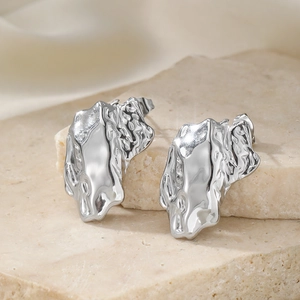 Macro detail of silver irregular earrings with lava texture on natural stone and silk