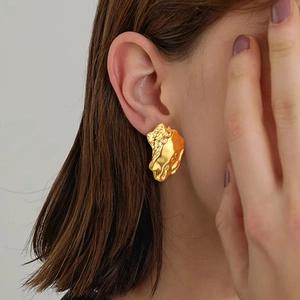 Detail of gold irregular lava texture stud earring shown on model with metallic finish