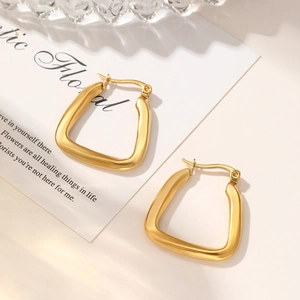 Detailed close-up of chunky gold geometric U-shaped hoop earrings with a polished finish