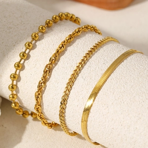Detail of four-piece gold chain bracelet set including snake, cuban, and ball links
