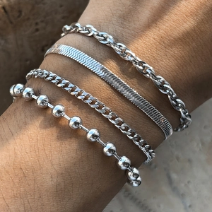 Macro view of four-piece layered silver metal bracelets set with curb and snake chains