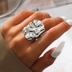 Makroaufnahme von glänzend silbernem Ring mit Wellenstruktur und Flüssigmetalldesign