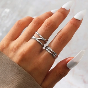 Detail of stacked silver geometric rings with crisscross and twisted band patterns