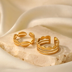 Close-up of golden geometric stackable open rings on stone with silk background
