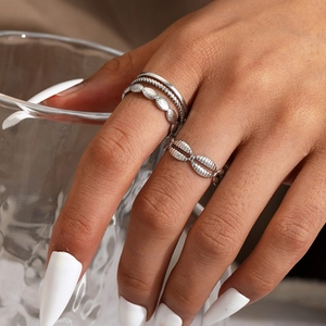 Detail of four-piece silver stacking rings featuring oval and shell designs on model's hand