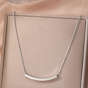 Minimalist silver smile pendant necklace with slender snake chain on display stand