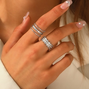 Close-up of stacked irregular silver stainless steel rings on a female model hand