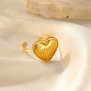 Macro detail of golden heart ring with radiant texture on smooth cream fabric