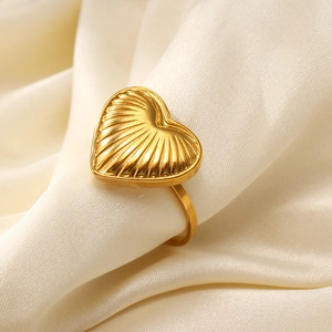 Detailed close-up of a gold heart ring with shell-like radial texture on white silk fabric