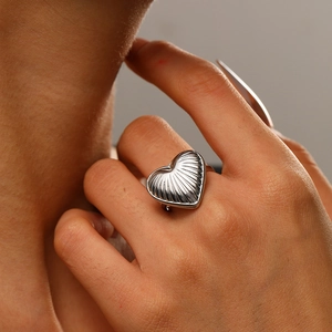 Macro shot of silver heart ring with vertical texture on model's finger