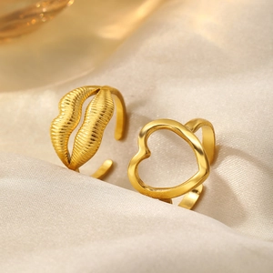 Detail of adjustable gold heart and lip shaped rings with textured finish on silk