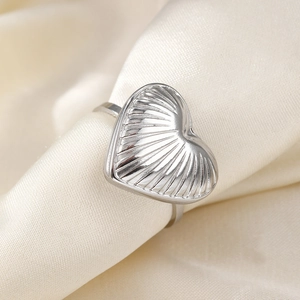 Polished stainless steel heart ring with textured radiating pattern on satin background