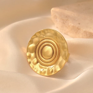 Detail view of large gold geometric ring with hammered texture on silk fabric