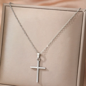 Minimalist silver stainless steel cross necklace for women on a jewelry display