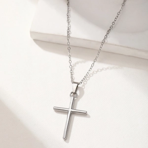Minimalist silver cross pendant necklace with a fine chain displayed on a white stand