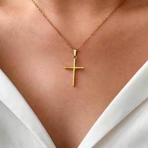 Close-up of polished gold cross necklace on model with elegant silk attire