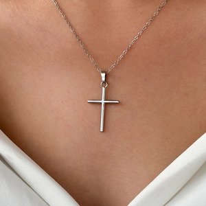 Silver cross pendant necklace on model showing delicate chain and minimalist style