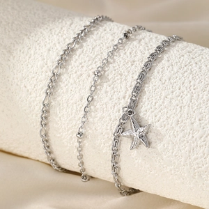 Three-piece layered silver anklet set featuring starfish charm and textured metal chains
