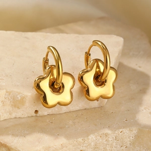 Boucles d'oreilles créoles fleurs en acier doré poli posées sur socle en pierre