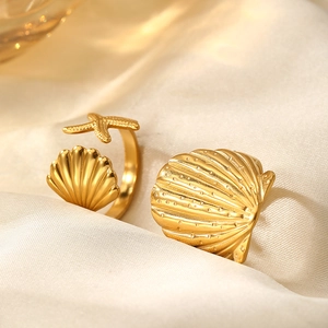 Macro shot of gold starfish and seashell rings on white silk fabric for beach style