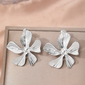 Elegant silver flower stud earrings with textured petals on a pink silk background