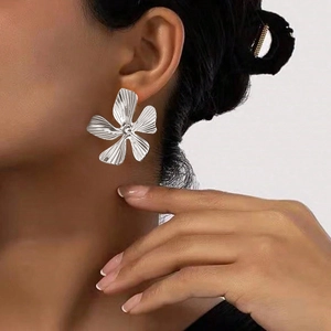 Close-up of oversized silver floral earrings with pleated petal texture on model