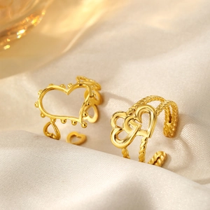 Close-up of gold heart rings with beaded edges and twisted rope band on silk