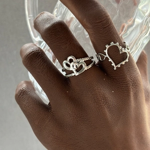 Detail of silver heart rings with twisted texture and beaded hollow design on finger