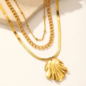 Detail view of gold layered necklace with cuban chain, snake chain and shell pendant