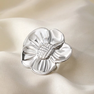 Polished silver sunflower ring with layered petal design on soft silk background
