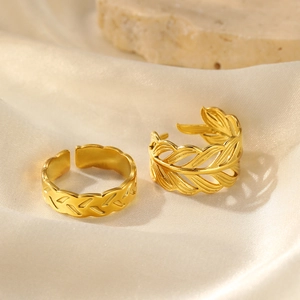 Detail of adjustable 18K gold plated leaf rings set on elegant silk and stone background