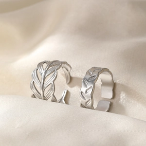 Adjustable silver leaf and V-pattern stainless steel rings on elegant silk fabric
