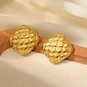 Close-up of elegant gold square earrings with quilted texture on white silk backdrop
