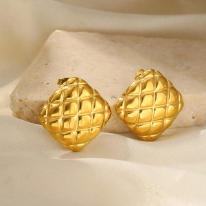 Detail of elegant gold square earrings with matelassé texture on beige stone display