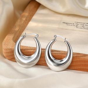 Polished silver stainless steel hoop earrings on a minimalist decorative wooden tray