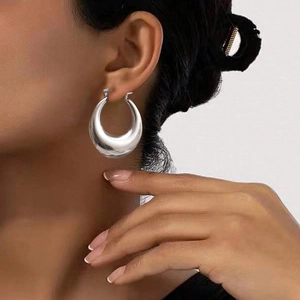 Polished silver stainless steel thick hoop earrings shown on model for fashion look