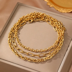 Three-piece gold layered chain anklet set featuring cable and paperclip links on velvet