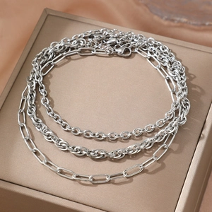 Three-piece silver chain anklet set featuring paperclip and textured links on jewelry box