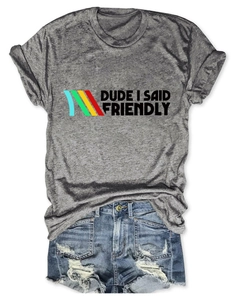 Flat lay of gray T-shirt with 'DUDE I SAID FRIENDLY' print and distressed denim shorts